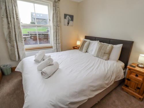 a bedroom with a large white bed with towels on it at Grey Croft in Embleton