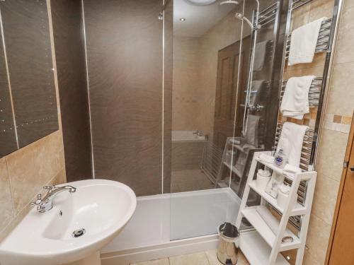 a bathroom with a shower and a sink and a tub at Grey Croft in Embleton