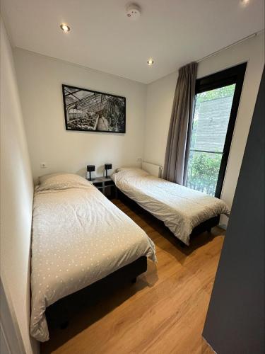 a bedroom with two beds and a window at Bad Hoophuizen Chalet L-Cube 6 Nr Eik 19 in Hulshorst