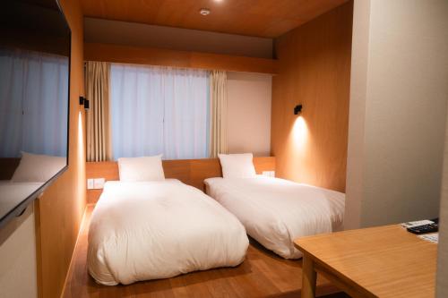 a hotel room with two beds and a table at Lake Side Inn MIRAHAKONE in Hakone