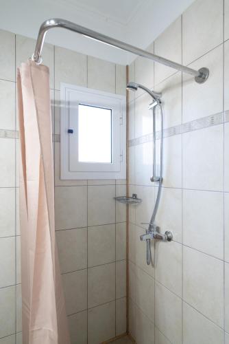 a shower with a window and a shower curtain at Casa Carina in Lakíthra