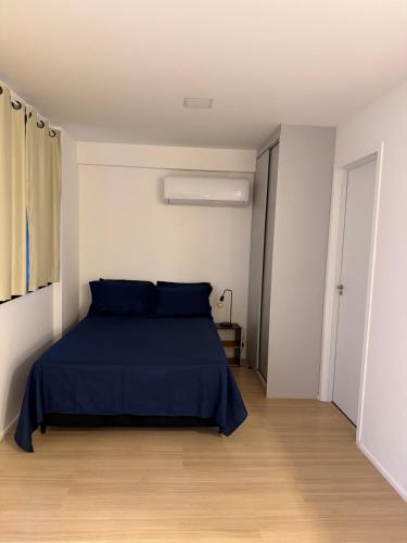 a bedroom with a blue bed in a white room at SeuLoft 110SouMais in Niterói
