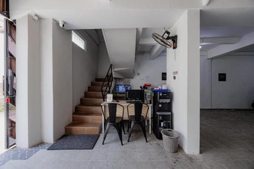 a room with a staircase and a table and chairs at Urbanview TeBeYe Syariah UNS Solo in Solo