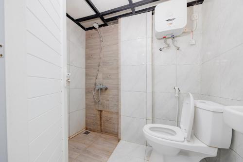 a white bathroom with a toilet and a shower at Urbanview TeBeYe Syariah UNS Solo in Solo