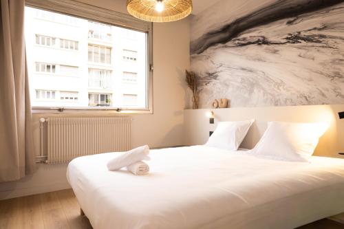 a bedroom with a large white bed with a window at Le Rhône - Aux Charmes Lyonnais ' in Lyon