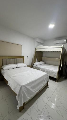 two beds in a room with white sheets at Serenity House in Santa Marta