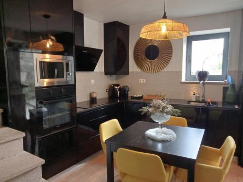 a kitchen with a table with yellow chairs and a microwave at Casa do beco Martinho in Viana do Castelo