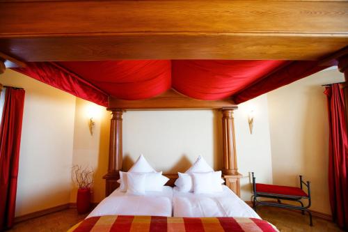 Burg & Gästehaus by Schwarzenstein في غيزينهايم: غرفة نوم بسرير وستارة حمراء