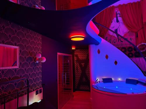 a bathroom with a tub in a room with purple lighting at Le 1920- Spa & Sauna privé- Love Room in Le Havre