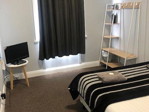 a bedroom with a bed and a desk with a computer monitor at white hart hotel murrurundi in Murrurundi