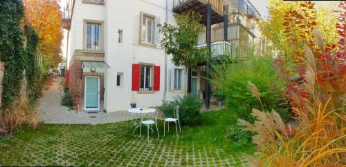 un giardino con tavolo e sedie di fronte a un edificio di Villa Schiller, 2 studios côté jardin - quartier Orangerie a Strasburgo