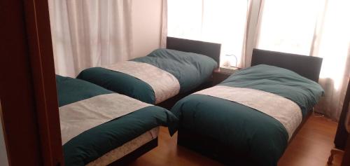 two twin beds in a room with a mirror at 桜庵 sakura an in Hatsukaichi