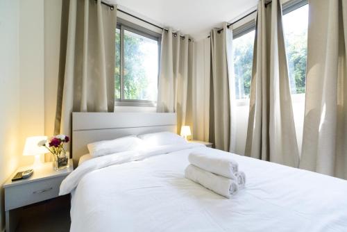 una camera da letto con un letto con lenzuola e cuscini bianchi di Dizengoff Inn Apartments a Tel Aviv
