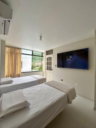 a bedroom with two beds and a tv on the wall at Alojamiento Jaén in Jaén