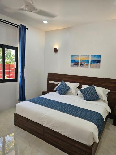 a bedroom with a large bed with blue and white pillows at Luma Boutique Hotel Omadhoo in Omadhoo