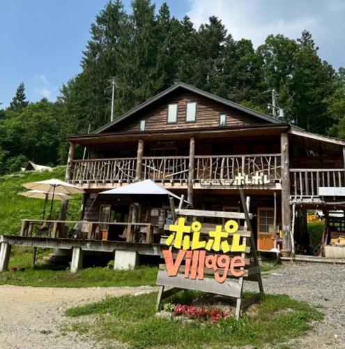 a large wooden house with a sign in front of it at ポレポレvillage in Urugi