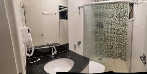a bathroom with a sink and a shower with a phone at Apto Mais Decor in Salinas