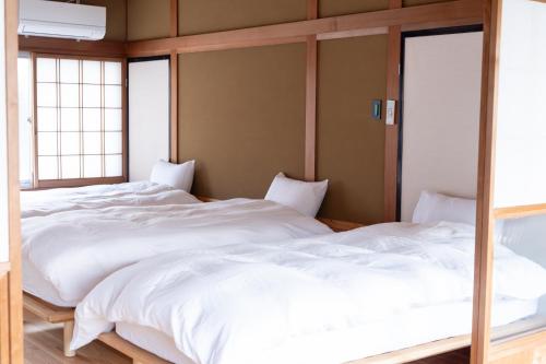 two large white beds in a room with windows at Kaitan雲津 in Matsue