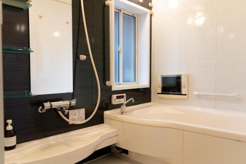 a bathroom with a tub and a sink and a tv at Kaitan雲津 in Matsue