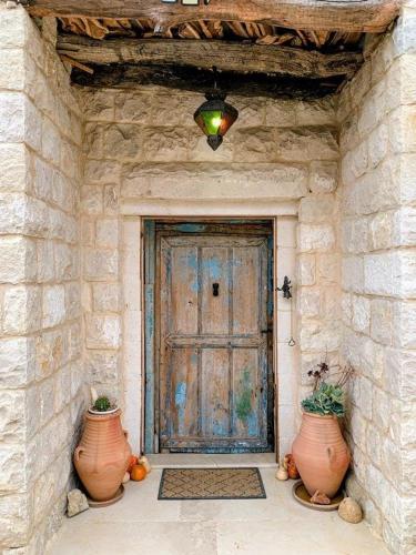 a front door of a stone building with two vases at Beit Al Rahi in Ḑahr al Ḩarf