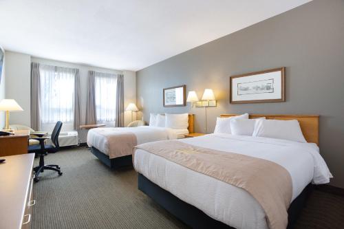 a hotel room with two beds and a desk at Lakeview Inns & Suites - Okotoks in Okotoks