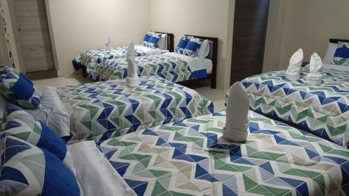 a room with three beds with blue and green at Refugio Volcán Tungurahua in Ambato