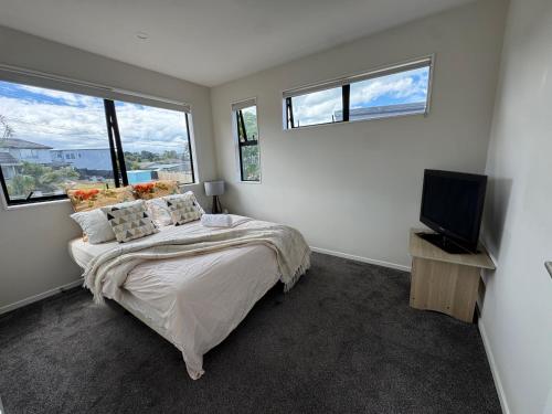 a bedroom with a bed and a flat screen tv at Duo Duo in Auckland
