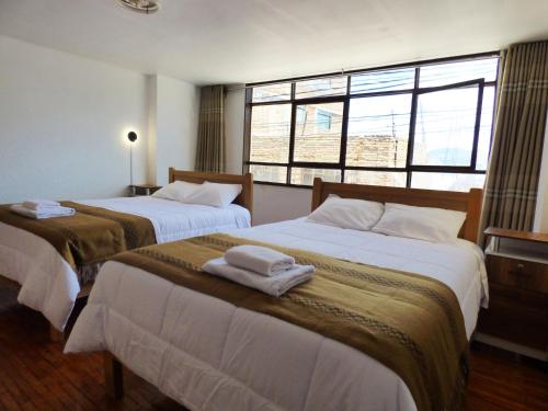 a bedroom with two beds with towels on them at Tierra Espiritual - Andean Holistic Hotel in Puno