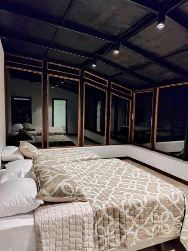 a large bed in a room with windows at Domo Fengari in Pululahua