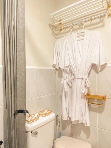 a bathroom with a white robe hanging on a rack at Gold-Themed Condo with Balcony and FREE Pool Access in Suba
