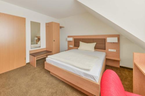 a bedroom with a bed and a red chair at Hotel Peterhof in Dietenheim