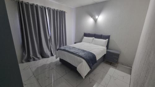 a bedroom with a bed and a window with curtains at 124 On Comet Oaks in Boksburg