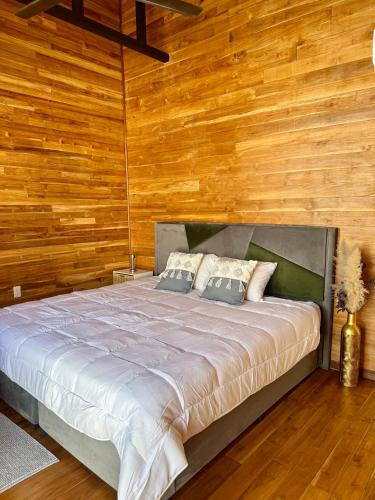 a bedroom with a large bed with wooden walls at Villa Republik in Parrita