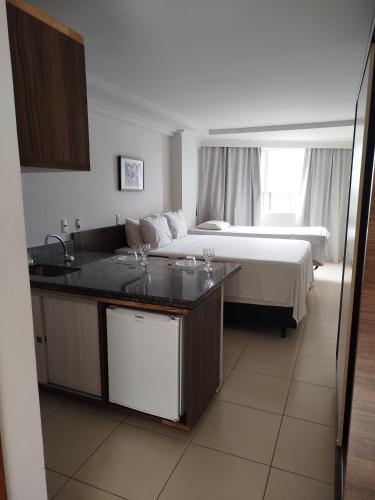 a hotel room with a bed and a kitchen with a sink at Flat Praia Cabo Branco João Pessoa in João Pessoa