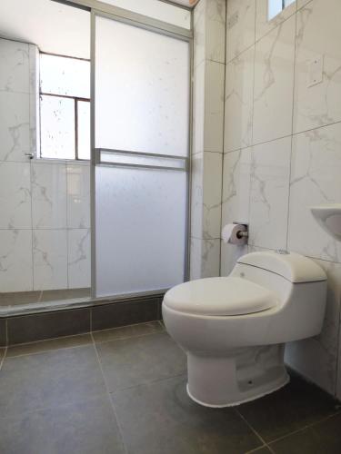 a white bathroom with a toilet and a shower at Tierra Espiritual - Andean Holistic Hotel in Puno