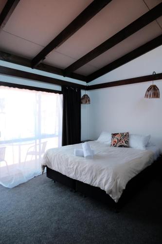 a bedroom with a bed and a large window at Tokaanu Retreat in Turangi