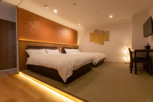 a bedroom with two beds and a table and a desk at Miro Hotel Dotonbori in Osaka