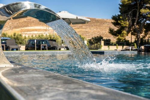 a water fountain in the middle of a swimming pool at Orion Eco Suites in Karteros