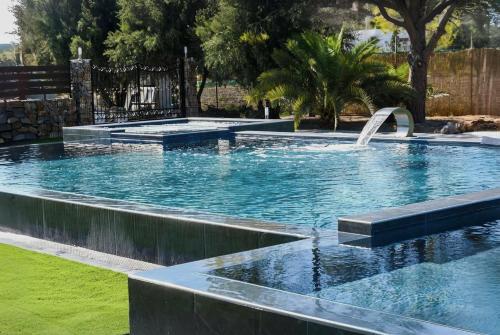 a large swimming pool with a fountain in a yard at Orion Eco Suites in Karteros
