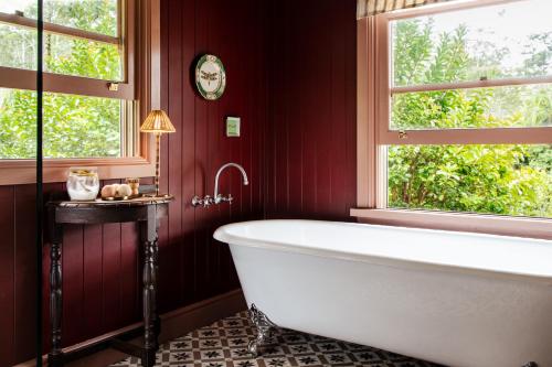 a bath tub in a red bathroom with a window at Nightcap Ridge - Byron Bay Hinterland in Dorroughby