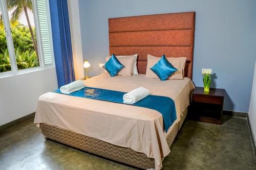a bedroom with a large bed with blue pillows at Coco forest camping in Kurunegala