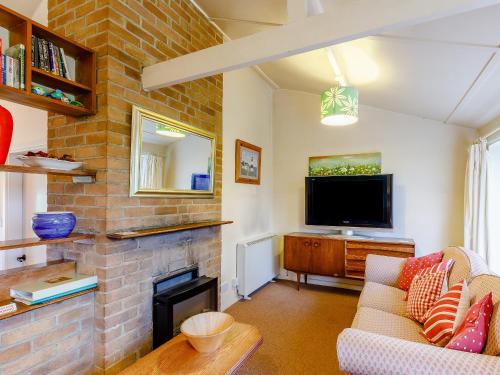 a living room with a fireplace and a tv at Hall Farm Bungalow in Shirley