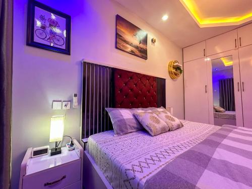 a bedroom with a large bed with a red headboard at Engeemos Bookastay Apartments in Abeokuta