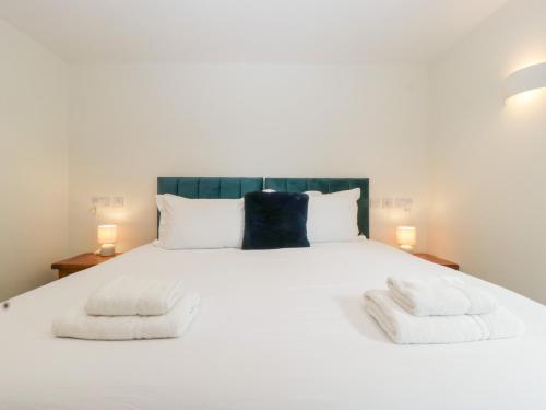 a bedroom with a white bed with two towels on it at Hidden Well in Bristol