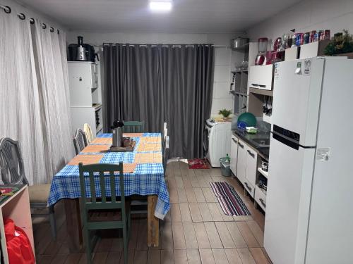 a kitchen with a table and a refrigerator at Praia do sonho, Quarto para até 4 pessoas super aconchegante in Palhoça