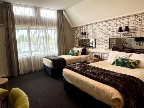 a hotel room with two beds and a brick wall at Ascot Park Hotel in Invercargill