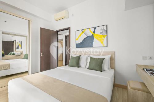 a white bedroom with a bed and a mirror at Elion by Kozystay - BSD in Samporo