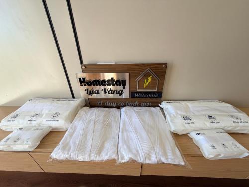 a bed with white sheets and a box of towels at Lúa Vàng homestay in Pleiku Airport
