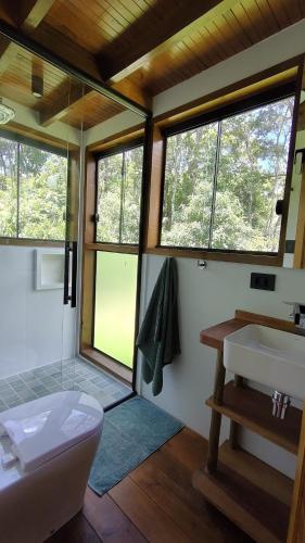 a bathroom with a toilet and a sink and windows at Floresta Mandaçaia in São Roque