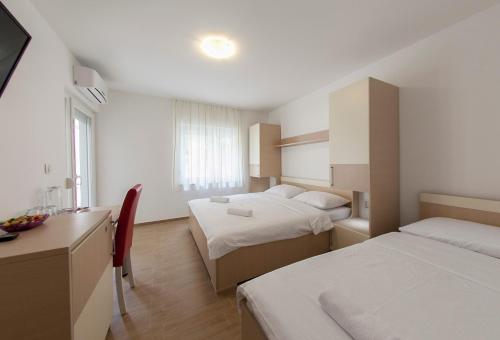 a hotel room with two beds and a desk at Villa Klara Guest House in Baška Voda